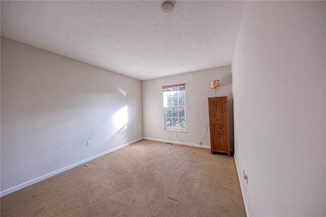 empty room with a textured ceiling and light colored carpet