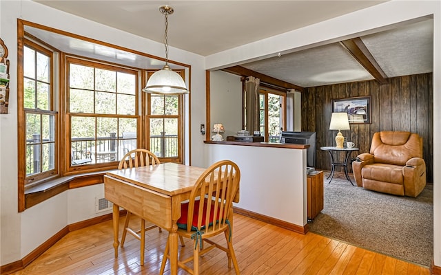 dining area featuring light hardwood / wood-style floors, beamed ceiling, and a wealth of natural light