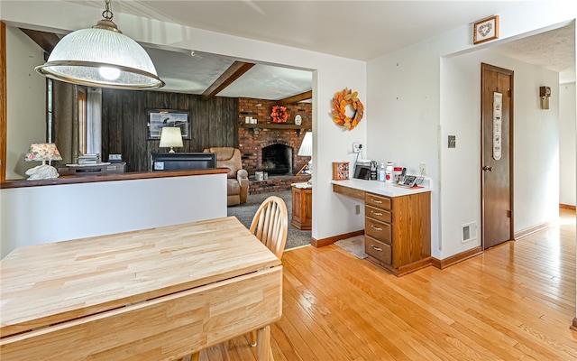 dining space featuring a fireplace, beam ceiling, and light wood-type flooring