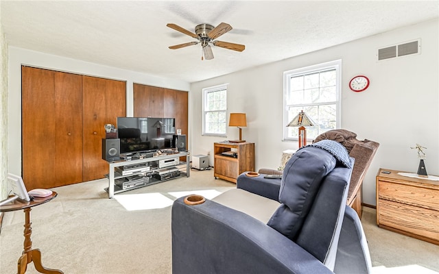 carpeted living room with a textured ceiling and ceiling fan