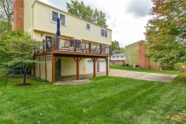 back of property with a wooden deck, a yard, and a garage