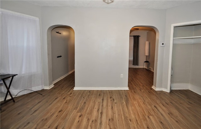 empty room with a textured ceiling and dark hardwood / wood-style flooring