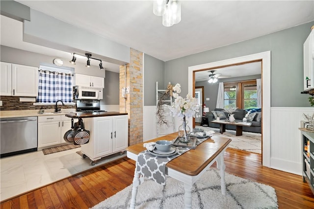 kitchen featuring sink, white cabinetry, tasteful backsplash, light hardwood / wood-style flooring, and appliances with stainless steel finishes