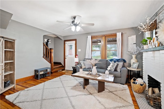 living room with ceiling fan, hardwood / wood-style floors, and a brick fireplace