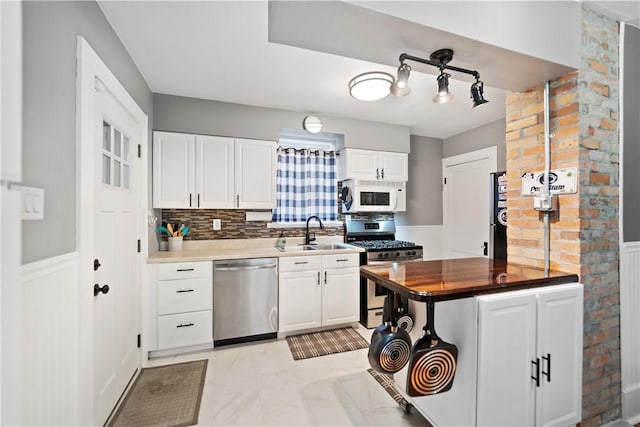 kitchen featuring wood counters, sink, white cabinets, backsplash, and stainless steel appliances