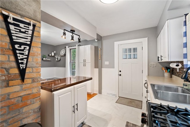 kitchen with white cabinetry, sink, and cooktop