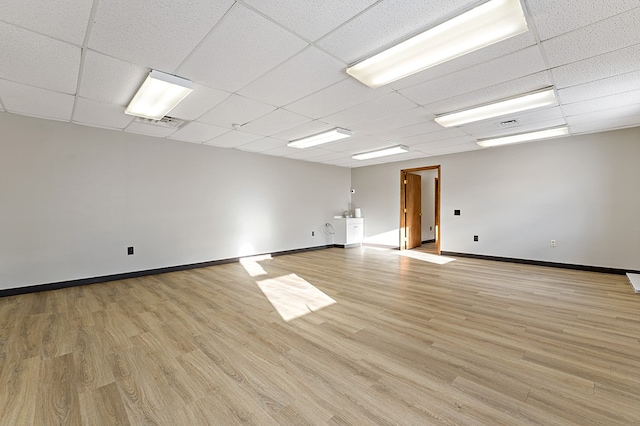 unfurnished room with a paneled ceiling and light hardwood / wood-style flooring