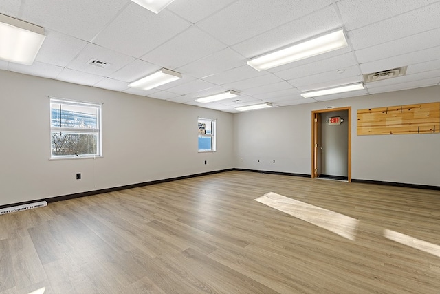 spare room featuring light hardwood / wood-style floors, a drop ceiling, and plenty of natural light