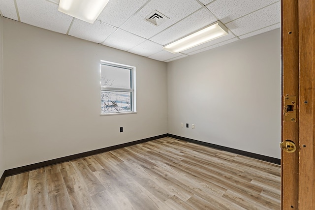 spare room featuring light hardwood / wood-style floors and a paneled ceiling