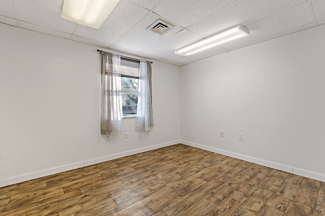 unfurnished room with a paneled ceiling and hardwood / wood-style floors