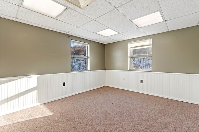 carpeted empty room with a drop ceiling