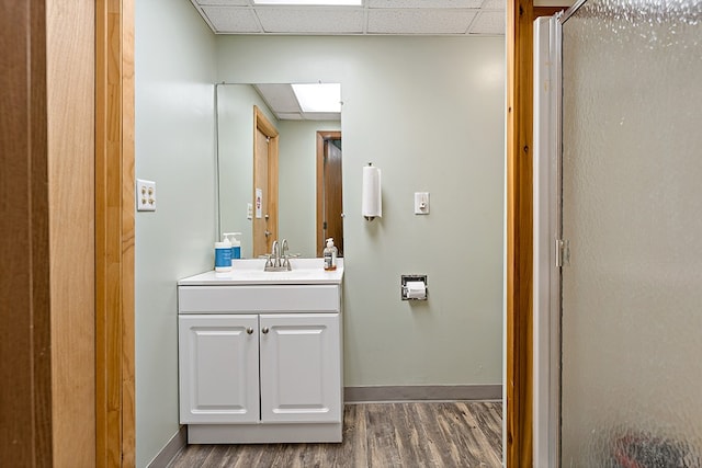 bathroom featuring vanity, hardwood / wood-style floors, a shower with shower door, and a paneled ceiling