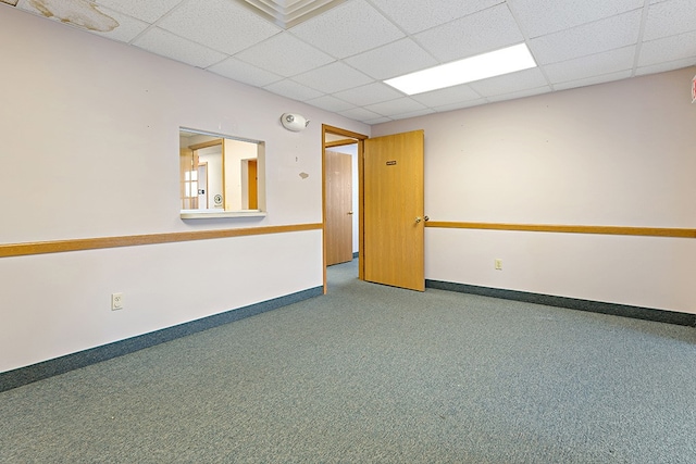 carpeted spare room with a drop ceiling