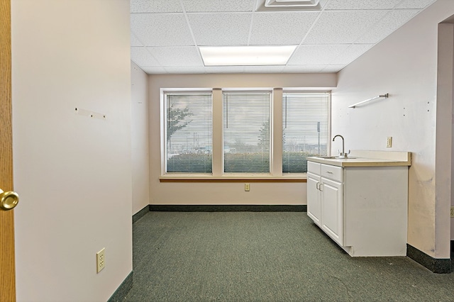 kitchen with a paneled ceiling, plenty of natural light, and dark colored carpet