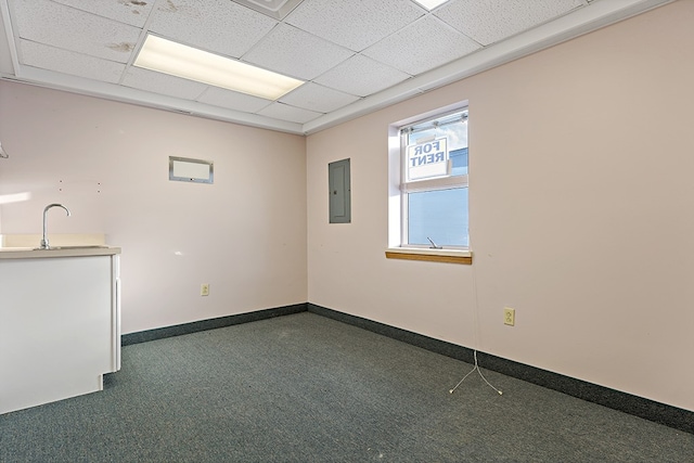 unfurnished room featuring a paneled ceiling, electric panel, sink, and dark carpet