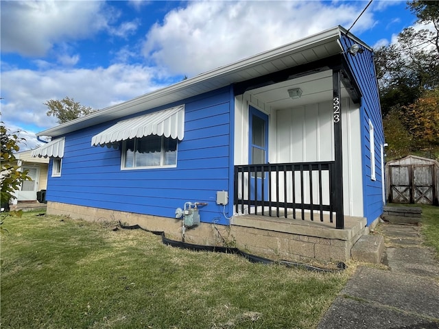 view of home's exterior featuring a porch, a yard, and a storage unit