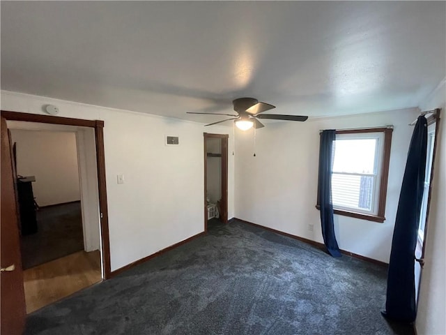 unfurnished bedroom with dark colored carpet and ceiling fan