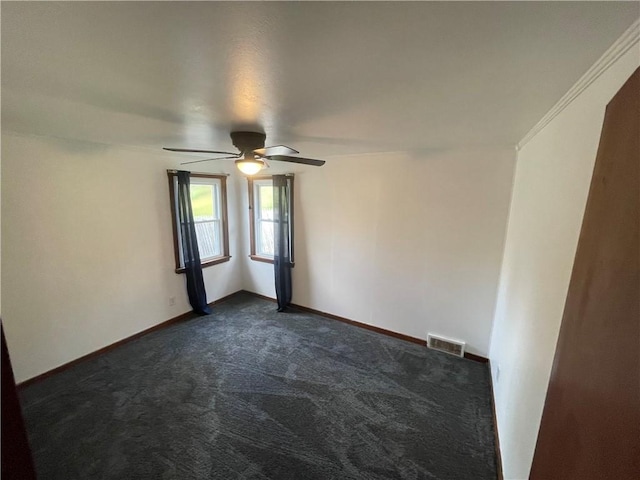 unfurnished room featuring dark carpet, ceiling fan, and crown molding