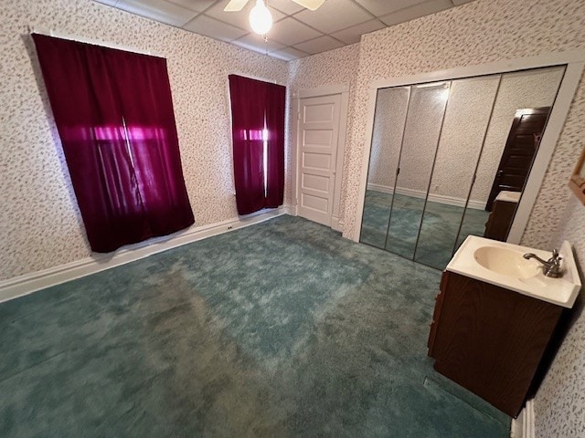 foyer with dark colored carpet, a paneled ceiling, sink, and ceiling fan