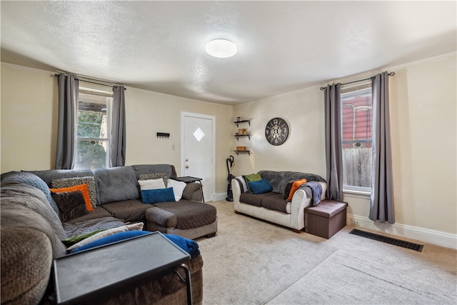 living room featuring a textured ceiling, light carpet, visible vents, and baseboards