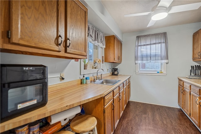 kitchen featuring brown cabinetry, dark wood finished floors, light countertops, and a sink