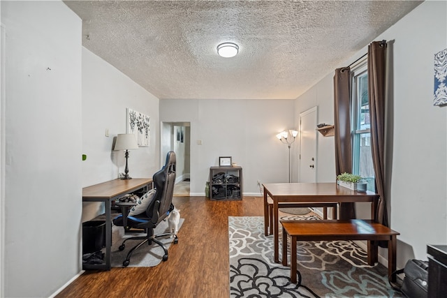 home office with a textured ceiling, baseboards, and wood finished floors