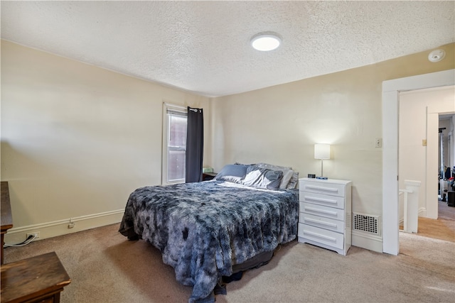 bedroom with a textured ceiling, baseboards, visible vents, and light colored carpet