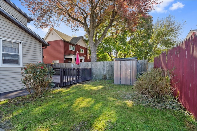 view of yard with a fenced backyard, a storage unit, a deck, and an outdoor structure