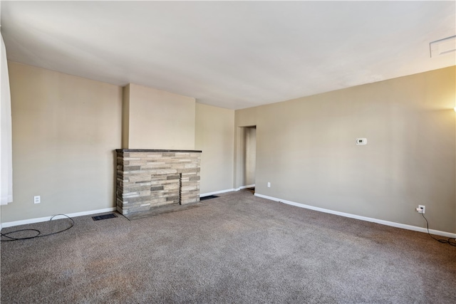 unfurnished living room with a stone fireplace, carpet flooring, visible vents, and baseboards