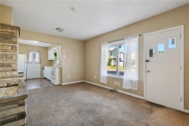 foyer with light carpet, a textured ceiling, and baseboards