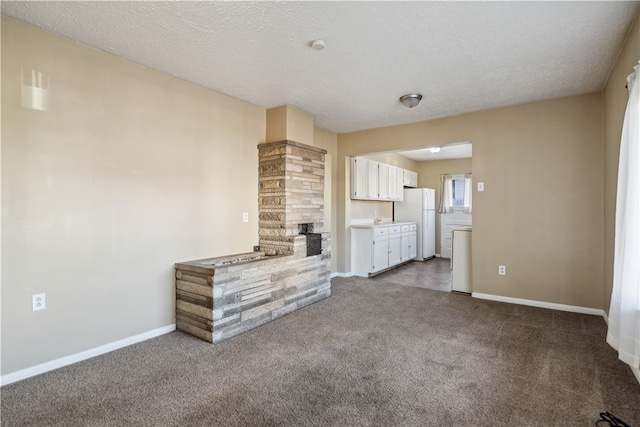 unfurnished living room with carpet, a fireplace, a textured ceiling, and baseboards