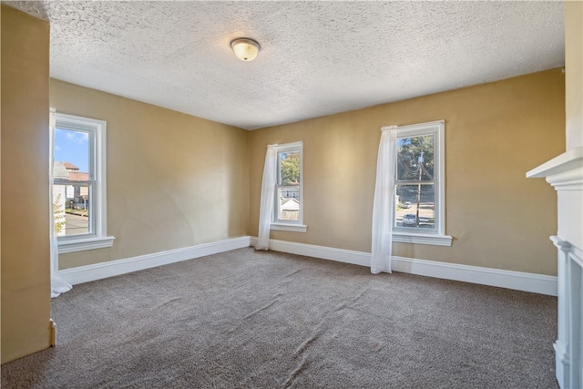 carpeted empty room featuring a healthy amount of sunlight, baseboards, and a textured ceiling