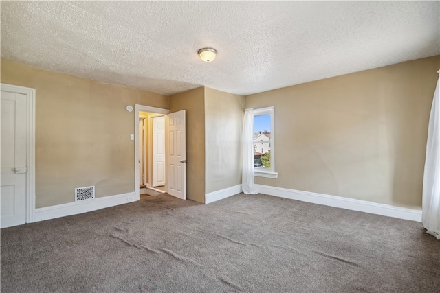 carpeted spare room featuring visible vents, a textured ceiling, and baseboards