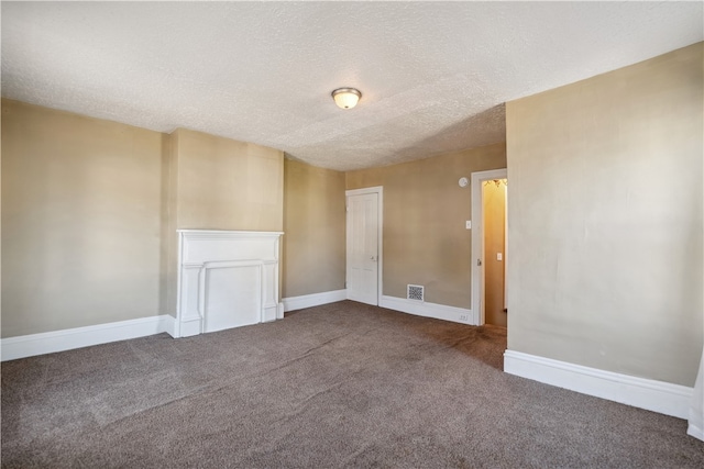 carpeted empty room with visible vents, a textured ceiling, and baseboards