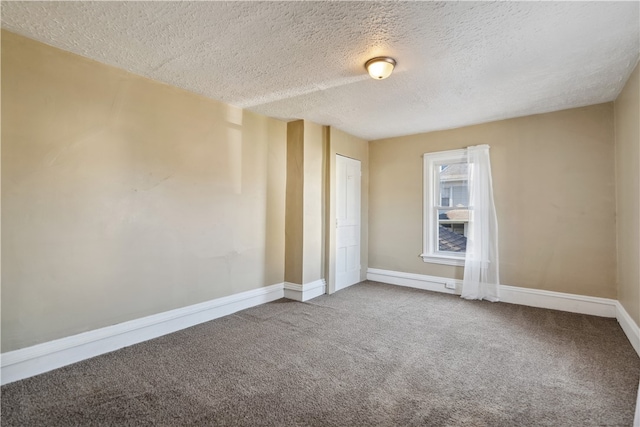 carpeted empty room with a textured ceiling and baseboards