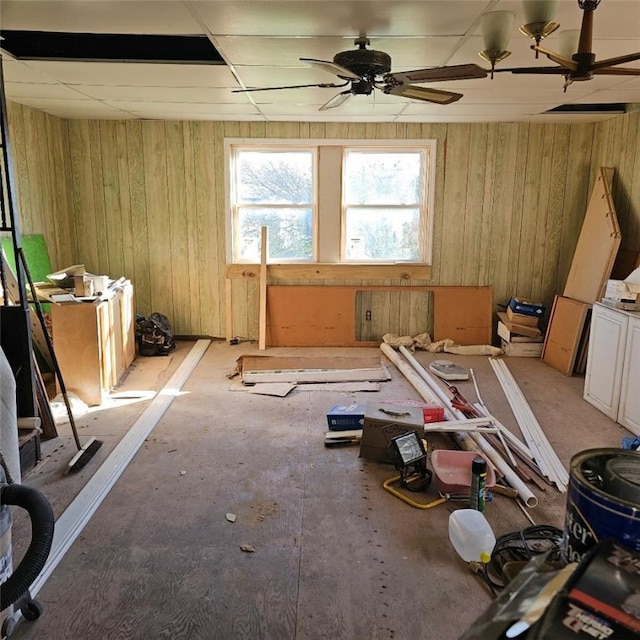 misc room featuring ceiling fan and wood walls