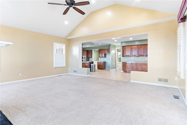 unfurnished living room featuring light carpet, high vaulted ceiling, and ceiling fan