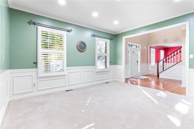 foyer entrance with ornamental molding and light colored carpet