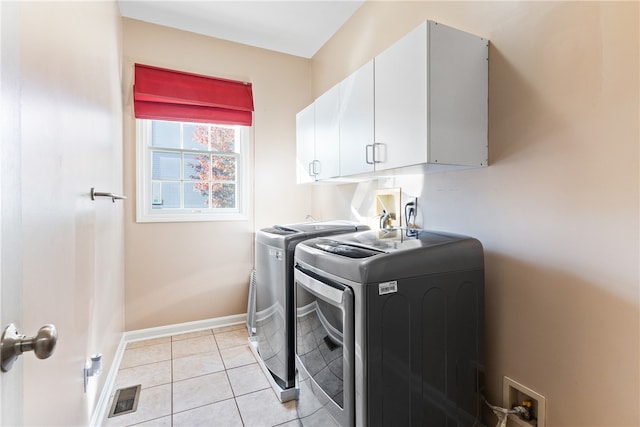 washroom with light tile patterned floors, cabinets, and washer and clothes dryer