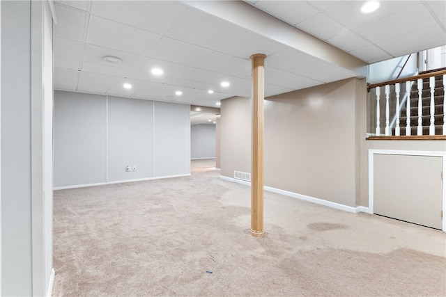 basement featuring light colored carpet and a paneled ceiling