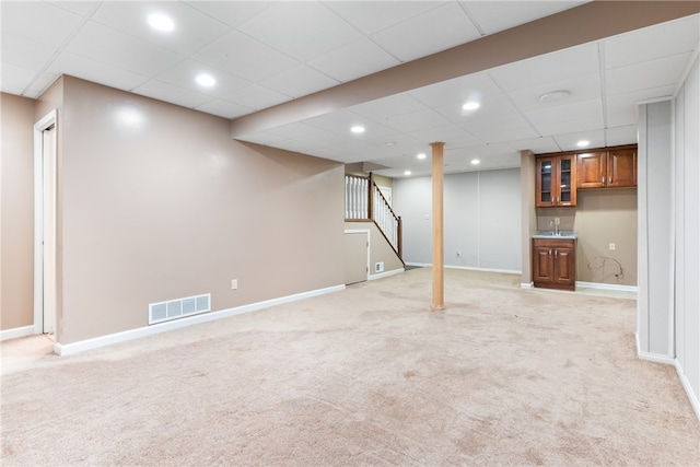 basement with light carpet, sink, and a paneled ceiling