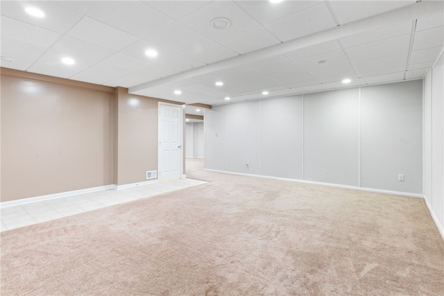 basement featuring a paneled ceiling and light colored carpet