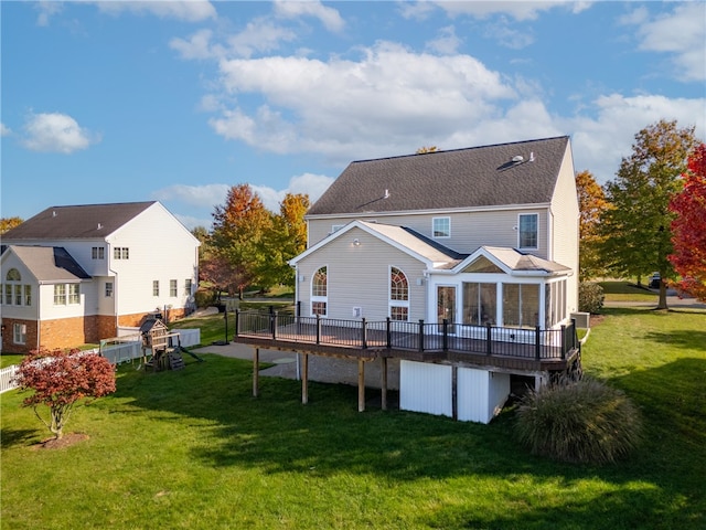 back of property featuring a wooden deck, a lawn, and a sunroom