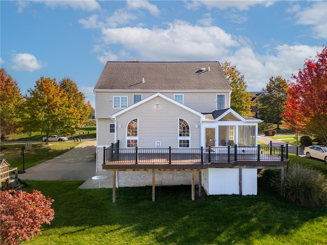 rear view of property featuring a wooden deck and a lawn