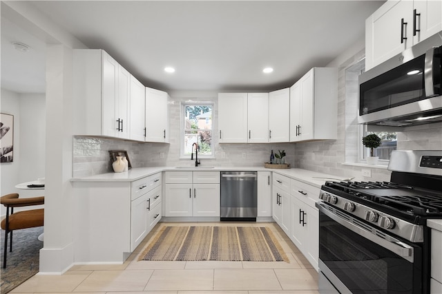 kitchen with backsplash, appliances with stainless steel finishes, sink, and white cabinets