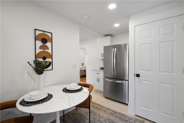 kitchen with stainless steel fridge, white cabinetry, and light tile patterned floors