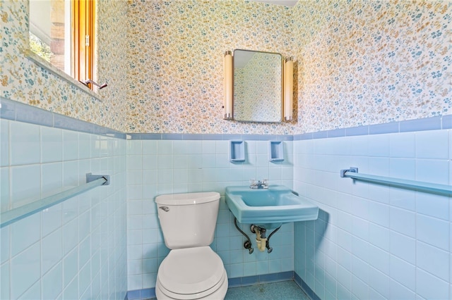 bathroom featuring toilet, sink, and tile walls