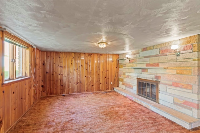 unfurnished living room featuring a fireplace, carpet floors, and wood walls