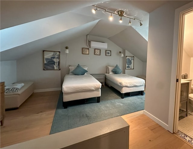 bedroom with an AC wall unit, hardwood / wood-style flooring, vaulted ceiling with skylight, and ensuite bathroom