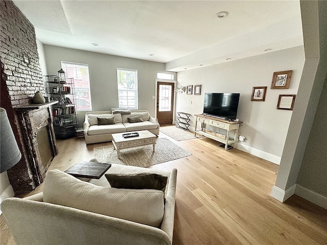 living room with a stone fireplace and light wood-type flooring